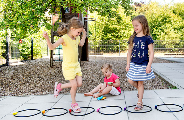 Motorik & Bewegung Kinder spielen Hüpfspiel im Garten