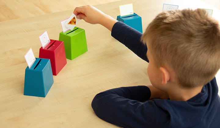 Kinder sitzt am Tisch und spielt mit Becherquizzer