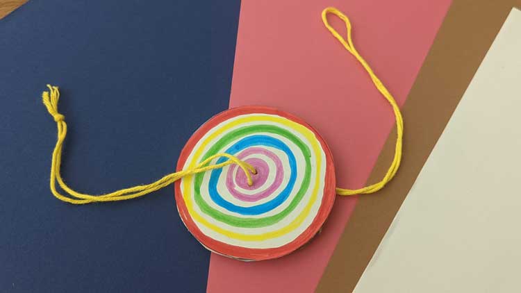 Mit Pappe, Papier und einem Wollfaden entsteht ein kreisender visueller Effekt.
